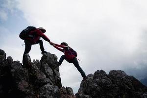 Person Wanderung Freunde helfen sich gegenseitig auf einen Berg. mann und frau geben eine helfende hand und einen aktiven fitten lebensstil. asien paar wandern helfen sich gegenseitig. konzept der freundschaft, teamarbeit. foto