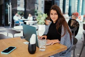 Porträt einer Studentin, die ein Netbook verwendet, während sie im Café sitzt foto
