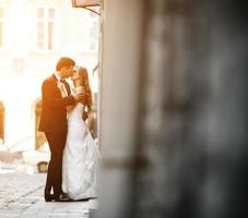 Schönes Hochzeitspaar, das sich in der Stadt küsst foto