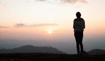 Silhouette einer Frau, die draußen in einer wunderschönen Landschaft auf dem Gipfel des Berges betet, kopieren Sie den Raum des Mannes, der die Hand auf den Gipfel des Berges und den abstrakten Hintergrund des Sonnenunterganghimmels erhebt. foto