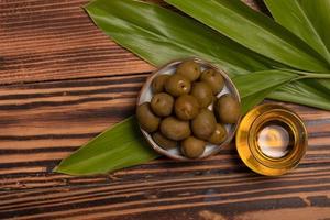 olivenöl mit olivenfrüchten auf holzhintergrund