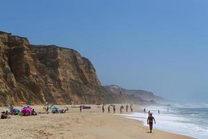 Strand am Meer mit Menschen, die sich ausruhen, Urlaubsort. Berge, Meer und Wellen. reise nach europa portugal. foto