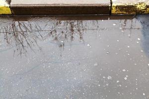 Oberfläche der Pfütze auf der städtischen Straße im Regen foto