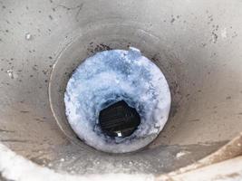 Blick auf gefrorenes Wasser und Eisloch im Betonbrunnen foto