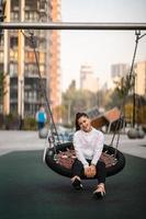 Junge Frau reitet auf einer Schaukel auf dem Spielplatz. foto