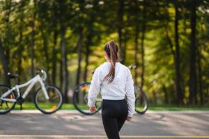 schönes Mädchen, das am weißen Fahrrad aufwirft. in der Natur spazieren gehen. foto