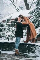 junger Mann und schönes Mädchen küssen sich in einem verschneiten Park foto