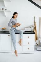 porträt einer freudigen frau isst zu hause ein leckeres croissant. foto