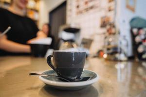 Tasse schwarzen Kaffee, Löffel, Holztisch, in einem Café foto