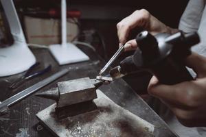 in der werkstatt lötet eine juwelierin schmuck foto