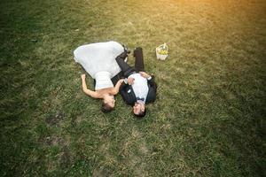 Hochzeitspaar, das auf dem Gras liegt foto