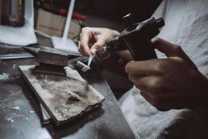 in der werkstatt lötet eine juwelierin schmuck foto