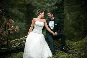 schönes Hochzeitspaar, das im Wald sitzt foto