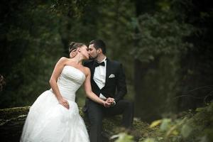 schönes Hochzeitspaar, das im Wald sitzt foto