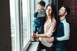 Vater, Mutter und Junge schauen aus dem Fenster foto