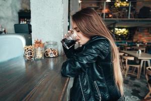 schönes Mädchen in einer schwarzen Jacke in einem Café foto