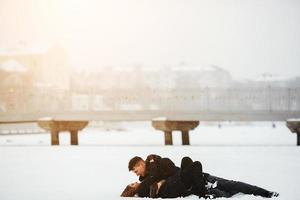 Mädchen und Kerl liegen auf Schnee foto