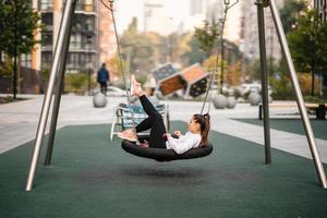 Junge Frau reitet auf einer Schaukel auf dem Spielplatz. foto