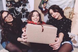 schönes Mädchen zeigt Weihnachtsgeschenke direkt in die Kamera. dekorative Vintage-Wohnung. foto