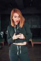 Europäische weiße rothaarige Frau hält Smartphone drinnen foto
