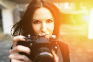 schöne Fotografin, die mit der Kamera posiert foto