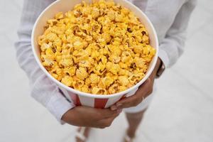 Nahaufnahmefoto eines jungen süßen Mädchens, das eine Tube Popcorn in ihren Händen hält. foto