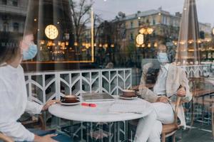 befreundete Mädchen trafen sich in einem Café. medizinische Schutzmasken tragen. foto