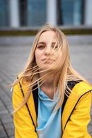 schöne junge blonde Frau auf der Straße, posiert mit Wind im Haar foto