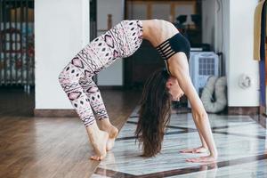 junge attraktive Frau, die Yoga in der Nähe des Fensters praktiziert foto