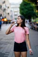 schönes junges Mädchen trinkt mit einer Flasche Wasser foto