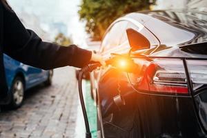 Frau in der Nähe von Elektroautos. Fahrzeug an der Ladestation aufgeladen. foto