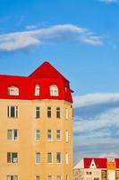 Wohnhochhaus mit rotem Ziegeldach gegen blauen Himmel. foto