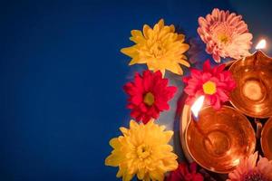 Frohes Diwali. feiert das indische lichtfest. traditionelle Diya-Öllampen und rote Blumen auf blauem Hintergrund foto