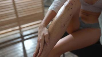 Frau trägt Anti-Cellulite-Peelingcreme auf ihr Bein auf foto