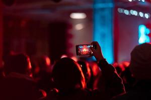 Person Nahaufnahme von Videoaufnahmen mit Smartphone während eines Konzerts. foto