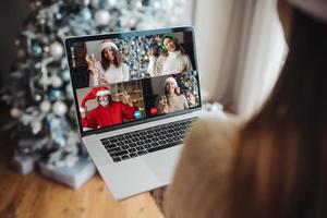 Frau mit Weihnachtsmütze, während sie mit einem Online-Freund auf dem Laptop spricht foto