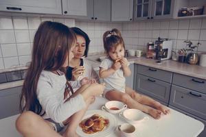 Mutter und zwei Töchter essen Pfannkuchen foto