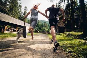 Paar läuft mit Hund auf der Straße in der Natur foto