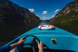 hübscher junger kerl steuert ein motorboot auf einem bergsee foto