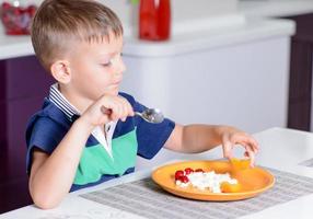 Junge, der Teller mit Käse und Obst isst