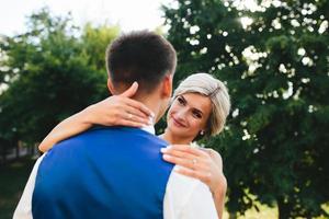 Schönes Hochzeitspaar, das sich im Park umarmt foto