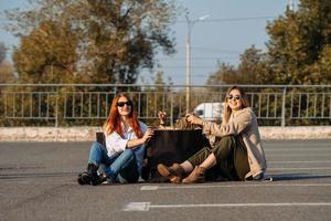 junge frauen mit einkaufstüten sitzen auf dem parkplatz foto