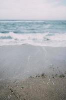 Meer mit den Wellen, die auf den Strand schlagen und Gischt erzeugen. foto