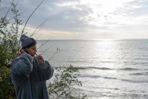 Frau, die ihre Zähne vor dem Hintergrund des Sonnenaufgangs am Meer putzt foto