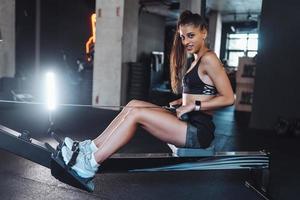 junge Frau trainiert und zieht Gewichte in sitzender Kabelrudermaschine. foto