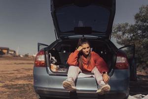attraktive junge Frau, die im Kofferraum eines Autos ruht foto