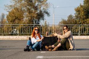 junge frauen mit einkaufstüten sitzen auf dem parkplatz foto