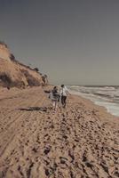 mann und frau erfreuen sich aneinander, laufen am meer entlang foto