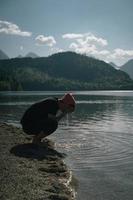 Ein Mann wäscht sich am Ufer eines Waldsees die Hände foto