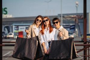 junge Frauen mit Einkaufstüten an einer Bushaltestelle foto